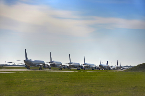 Multiple grounded airplanes parked on the runway. Worldwide the airline industry has been taking a hard financially hit due to the Covid - 19, Corona Virus Pandemic.