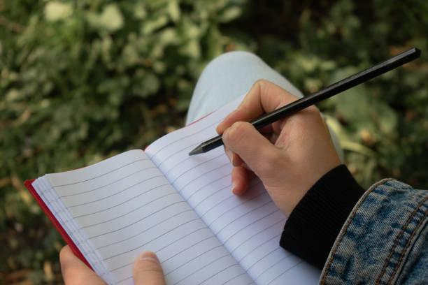 istock Lady's hand preparing to write on a blank sheet of a red notebook 1225959731