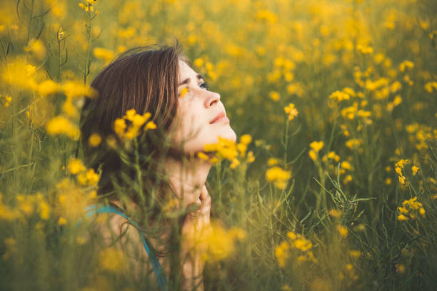 beautiful romantic girl on blooming rapeseed field looking up, young woman walking, pretty female face, concert emotions, inspiration beautiful romantic girl on blooming rapeseed field looking up, young woman walking, pretty female face, concert emotions, inspiration hiding place stock pictures, royalty-free photos & images