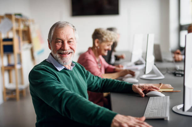 Portrait of senior man attending computer and technology education class. Portrait of senior man attending computer and technology education class, looking at camera. community center stock pictures, royalty-free photos & images