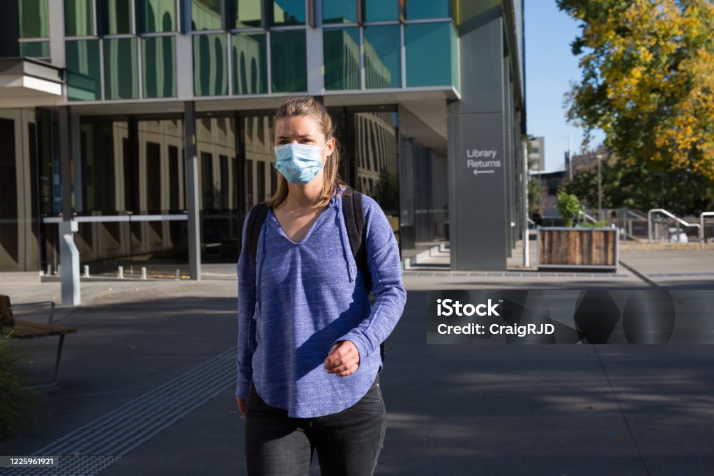 Student Wearing Mask Leaving Library Building Close up of a female student wearing a face mask as she leaves the library building. University Stock Photo