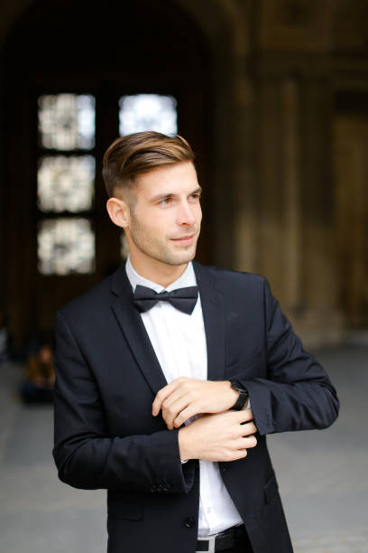 istock Young man standing and posing, wearing black suit and bow tie 1225962765