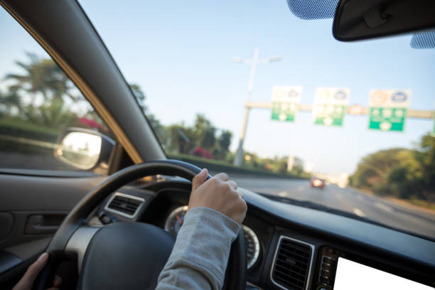 istock People hands holding steering wheel while driving car on city road 1225963703