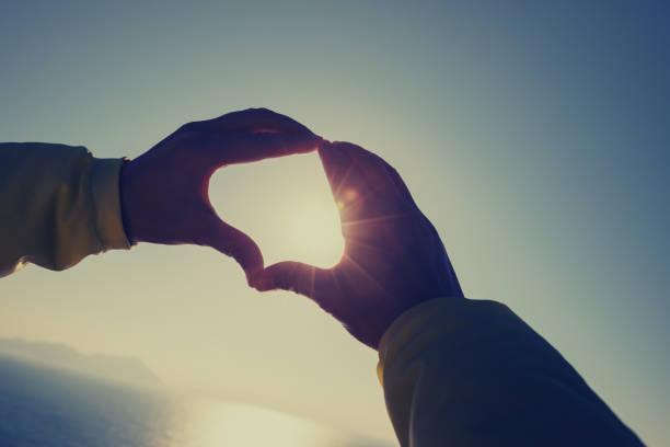 istock Holding hands in heart shape at sunrise beach 1225963768