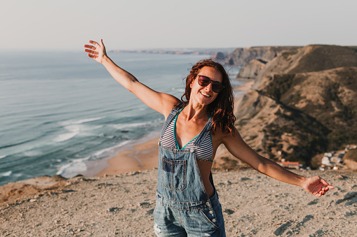 beautiful happy young woman on the top of a hill with arms wide open. Summer time. Lifestyle