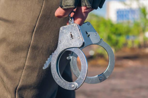 наручники в руках полицейского крупным планом. часть полицейского оборудования - 2657 стоковые фото и изображения