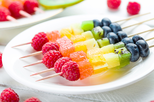 Fruit kebab on a white plate close-up. Beautiful and healthy food