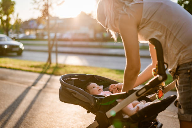 Mother and newborn baby on sunset Family walk around the neighborhood. Single mother is taking care of newborn baby while walking on sunset. Baby is in stroller. pushchair stock pictures, royalty-free photos & images