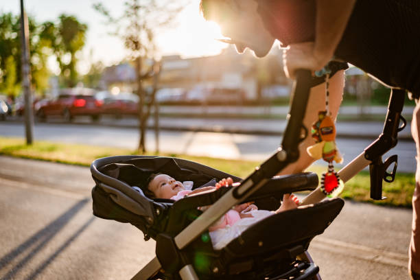Father and newborn baby walking on sunset Family walk around the neighborhood. Single father is taking care of newborn baby while walking on sunset. Baby is in stroller. pushchair stock pictures, royalty-free photos & images