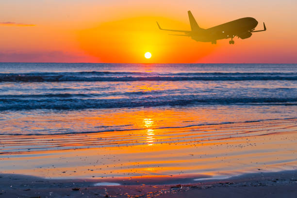 istock airplane fly over a sea beach at the sunset 1225974780