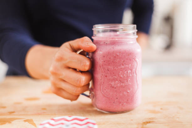 istock Homemade fruit smoothie in hand on a wooden kitchen table 1225981857