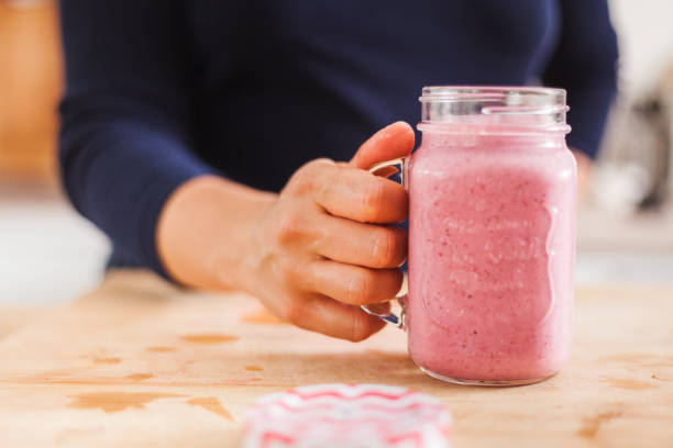 istock Homemade fruit smoothie in hand on a wooden kitchen table 1225981858