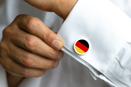 Man in white shirt wearing cufflinks. German Flag on cufflinks.