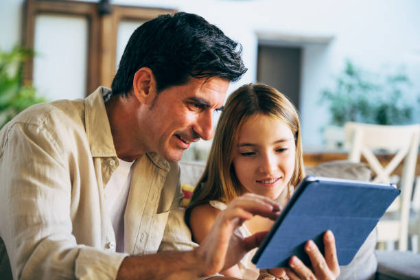 istock Spanish father and preteen daughter using digital tablet 1225985470