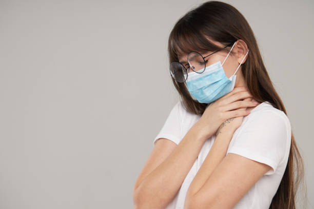 istock Asian woman in face protective mask feeling unwell  on grey studio background. Copy space for text. The first defense against the epidemic of flu and coronavirus 1225985540