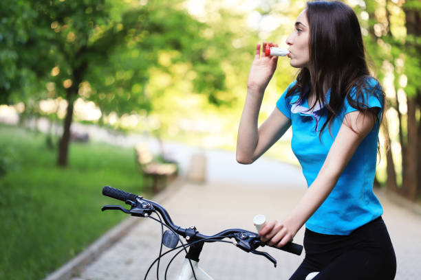 istock Young woman using asthma inhaler while riding a bike 1225986074