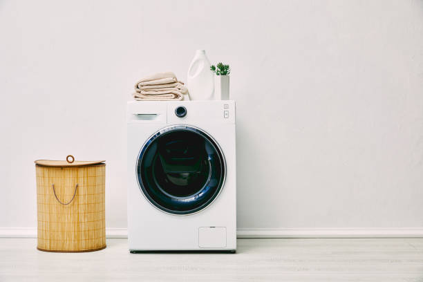 detergent bottle, towels and plant on washing machine near laundry basket in bathroom detergent bottle, towels and plant on washing machine near laundry basket in bathroom utility room stock pictures, royalty-free photos & images