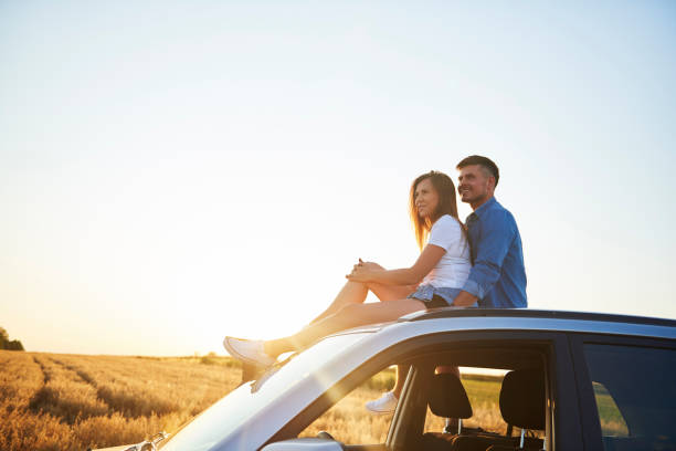 istock Young couple sitting on car and looking straight ahead. 1225992398