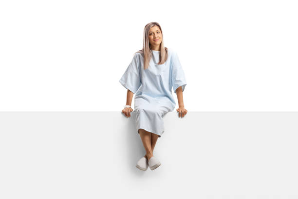 paciente femenina en una bata de hospital sentada en un panel en blanco - vestido de noche fotografías e imágenes de stock