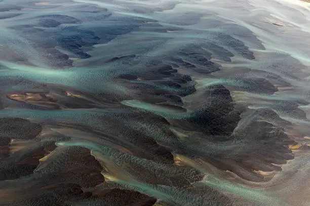 Curvy flow of glacial rivers through a dream-like landscape of Iceland, taken from a helicopter.