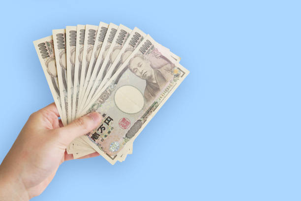 istock A man's hand holding a Japanese yen.blue background. 1225998929