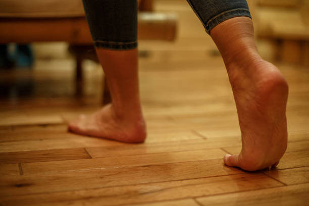 giovane donna irriconoscibile che cammina a piedi nudi sul pavimento di legno - il prossimo passo foto e immagini stock