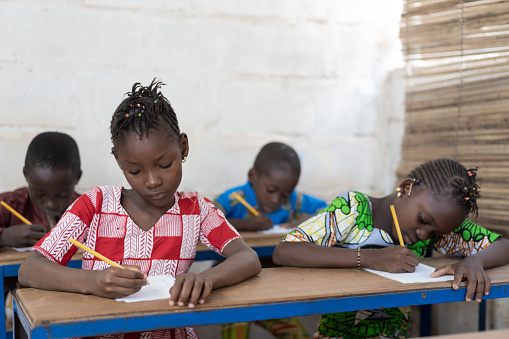 Four gorgeous African Black Children Sitting in Desks. Candid picture of African children in a School Building.