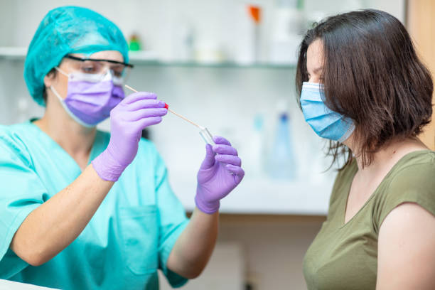 istock Female doctor in protective workwear preparing swab for testing female patient 1226004820
