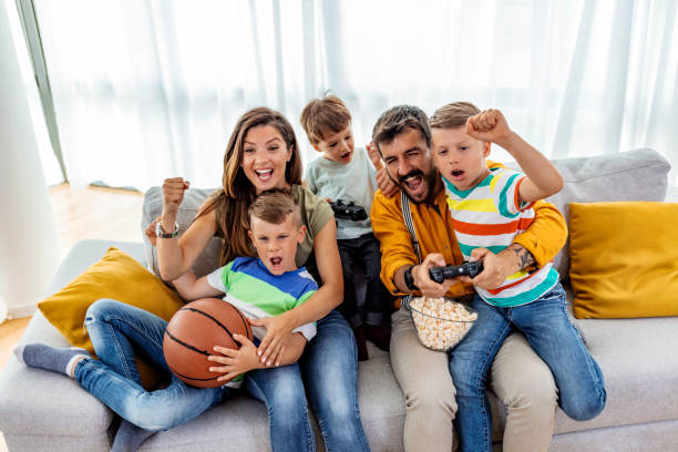 happy family playing video games at home and having fun together - gamer watching tv adult couple imagens e fotografias de stock