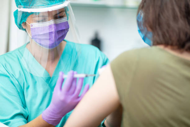 istock Nurse in protective workwear injecting flu vaccine with syringe 1226005922