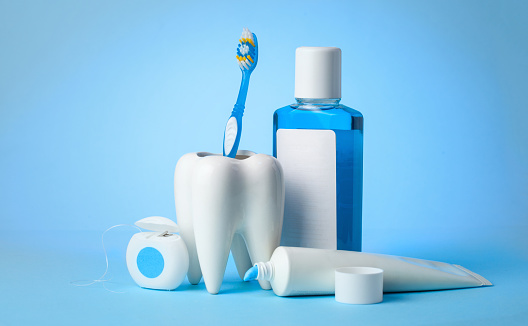 Set for cleaning teeth and mouth. Toothpaste, toothbrush, dental floss and mouthwash on a blue background. Copy space for text
