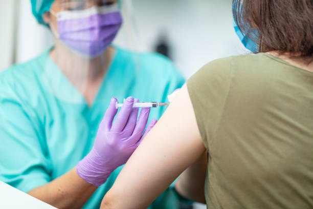 istock Healthcare worker in protective workwear injecting flu vaccine 1226006002
