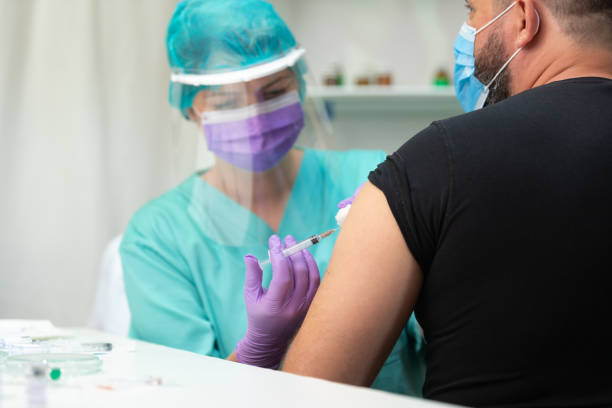 istock Nurse in protective workwear injecting flu vaccine in man's arm 1226006201