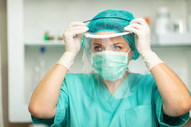 istock Female doctor wearing protective mask and putting visor on 1226009427