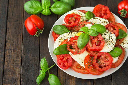 Fresh caprese salad with mozzarella, tomato, basil and spices on the plate