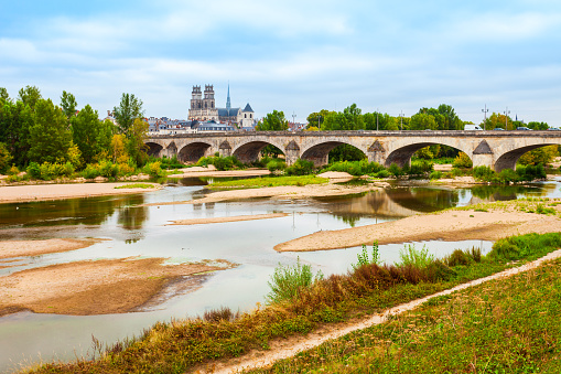 Orleans cathedral and bridge through Loire river. Orleans is a prefecture and commune in north central France.