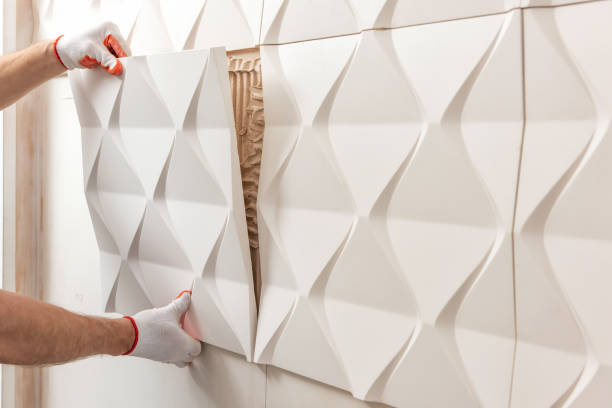 Installation of gypsum 3D panel. Installation of gypsum 3D panel. A worker is attaching the gypsum tile to the wall. control panel stock pictures, royalty-free photos & images