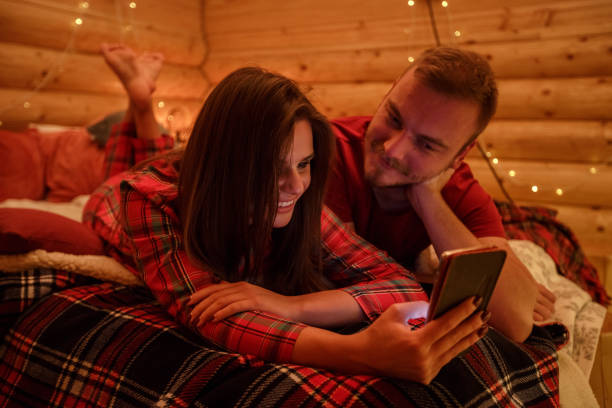 istock Romantic young couple lying in bed and watching video on a smart phone together 1226018044