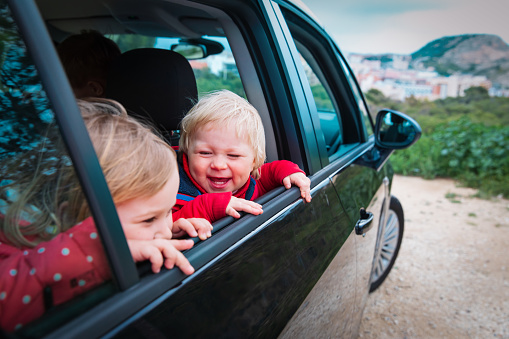 happy kids travel by car on road in nature, family auto trip