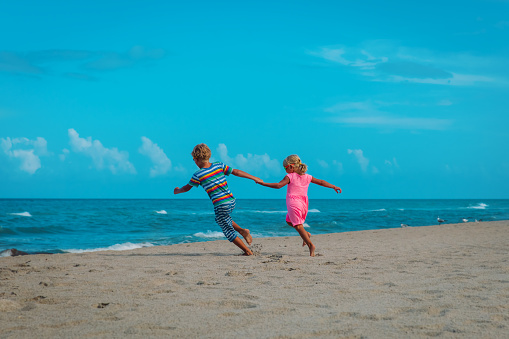 little boy and girl running on beach, kids enjoy sea vacation, family at sea