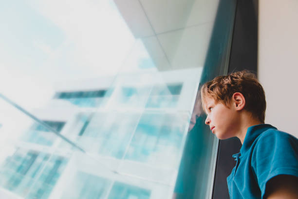 boy feeling anxiety and stress from social isolation, kid looking at the window mental issues of staying home