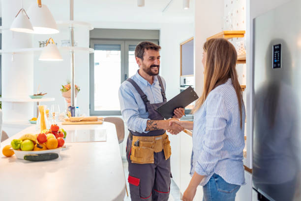 It's a pleasure doing business with you Young Woman Shaking Hands To Male Plumber With Clipboard In Kitchen Room plumber stock pictures, royalty-free photos & images