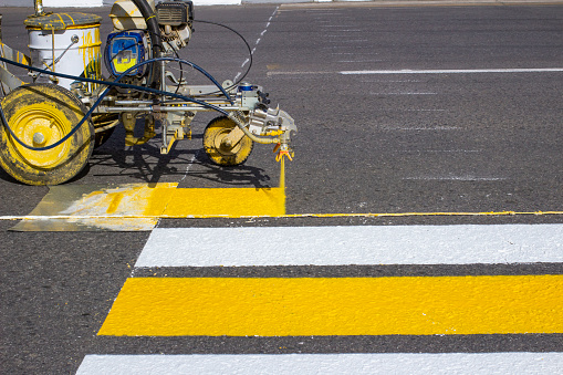 Road workers use hot-melt scribing machines to painting pedestrian crosswalk on asphalt road surface in the city.