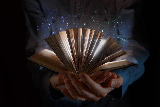 Human hand holding magic book with magic lights stock photo