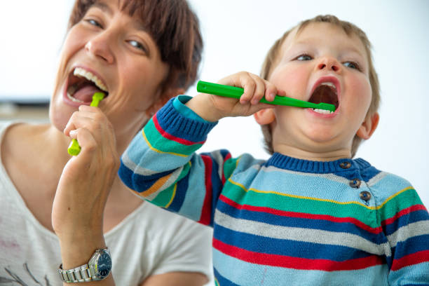 glückliche mutter und sohn genießen zähne zusammen vor weißem hintergrund - stockfoto - child brushing human teeth brushing teeth stock-fotos und bilder