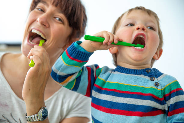 szczęśliwa matka i syn ciesząc się szczotkowanie zęby razem na białym tle - zdjęcie stockowe - child smiling human teeth dental hygiene zdjęcia i obrazy z banku zdjęć