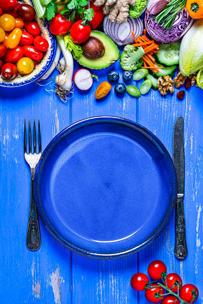 istock Vegan food: empty blue plate and healthy fresh vegetables border. Copy space 1226030858