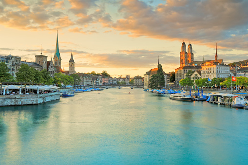This photo was taken during the golden hour during sunset from the Quaibrücke.  At the very far distance is the Minster Bridge (Münsterbrücke).  This is a very popular tourist destination due to many historic churches, cathedrals, clock towers, and old town buildings along The Limmat riverbank.  This is also an iconic and epic skyline of Zurich.