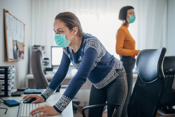istock Two women working in office with protective masks 1226039072