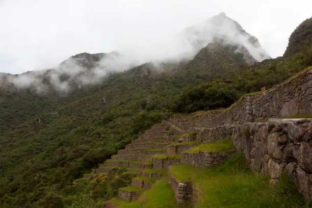Spiritual morning mist rises over Inca head mountain at Machu Picchu with Huana Picchu in background.